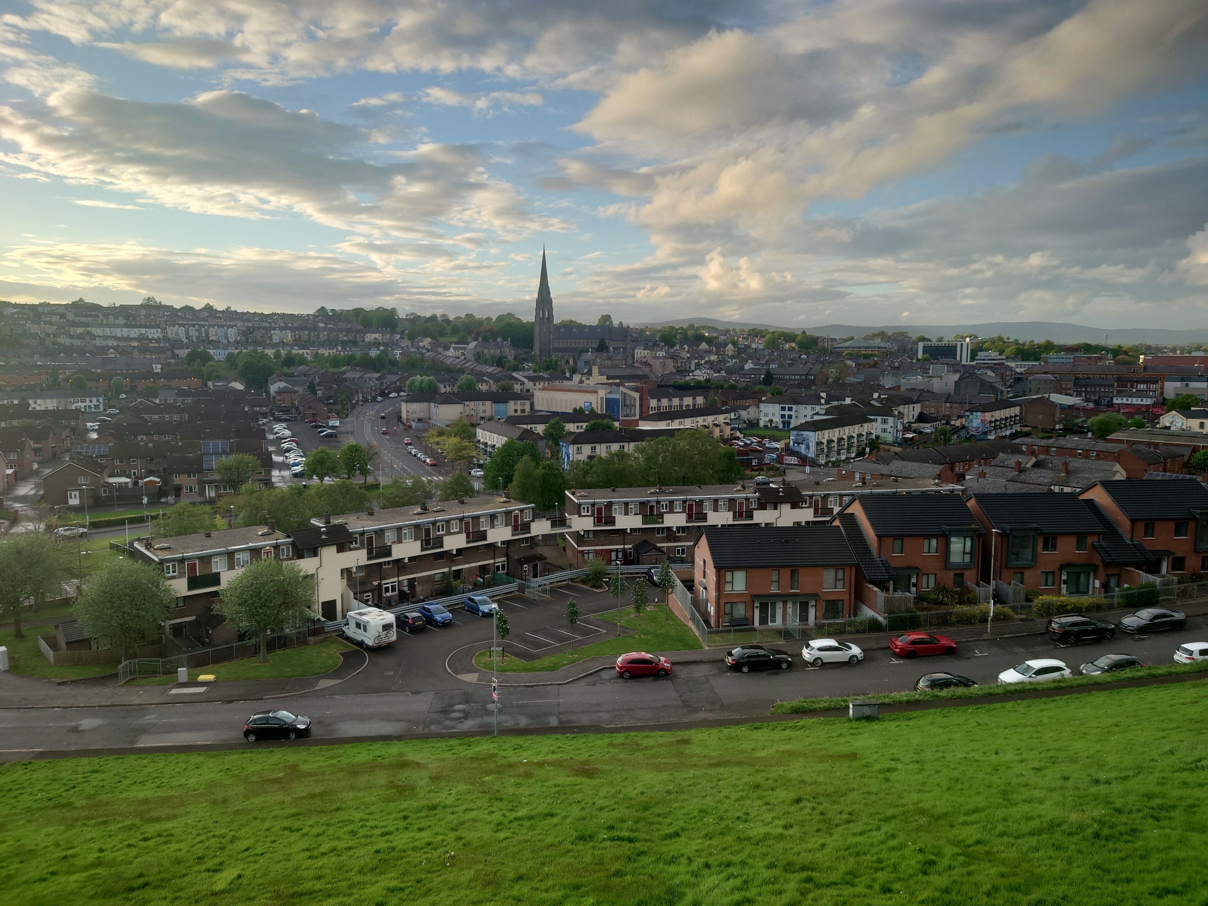 A residential area with houses, a church spire, and a parking lot.