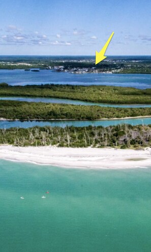 A coastal landscape with clear turquoise waters, sandy beaches, and dense greenery.