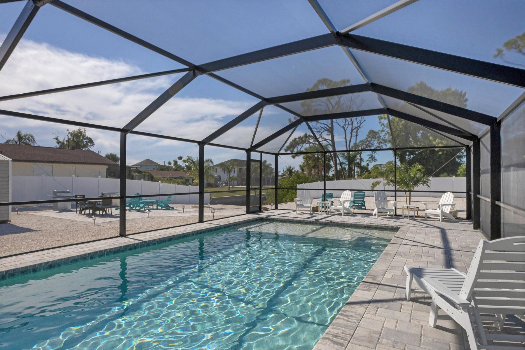 A covered swimming pool with clear water, surrounded by lounge chairs and a patio area.