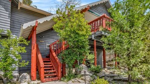 A wooden staircase leading to a porch with a stone wall and greenery. - Bass Lake Cabin—Game Room—BBQ—5:4—Boat Slip (Bass Lake)