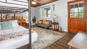 A cozy room with a bunk bed, a sofa, a wooden ceiling, and a large window. - Bass Lake Cabin—Game Room—BBQ—5:4—Boat Slip (Bass Lake)