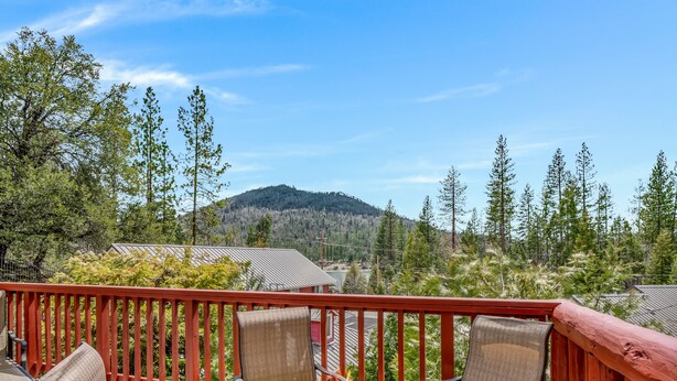 A deck with a fire feature, chairs, and a view of a forested mountain. - Bass Lake Cabin—Game Room—BBQ—5:4—Boat Slip (Bass Lake)