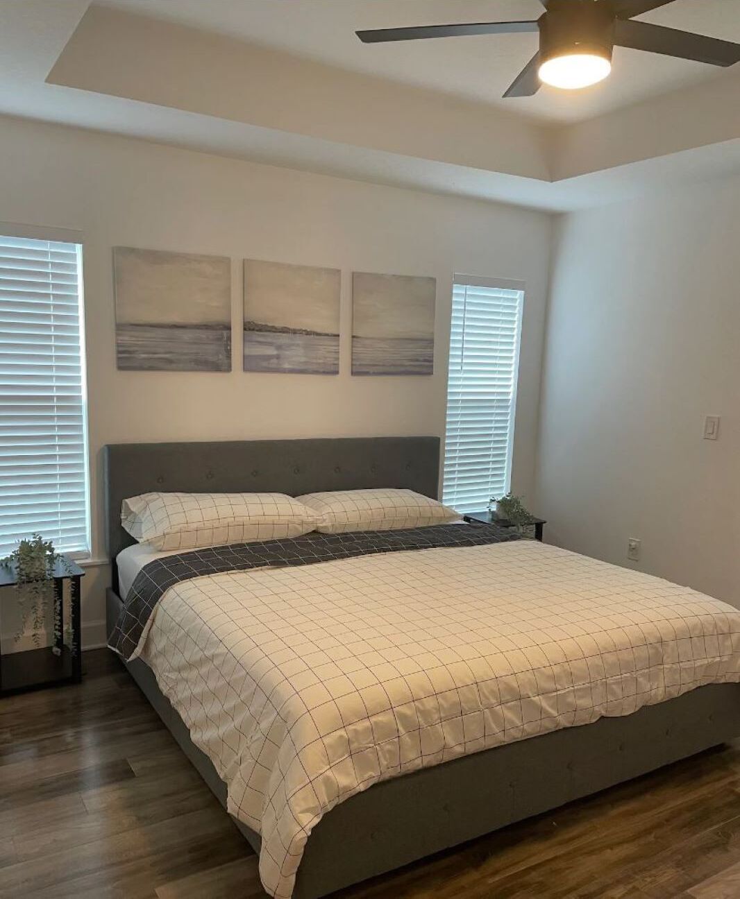 Un dormitorio con una cama, un ventilador de techo y obras de arte en la pared.