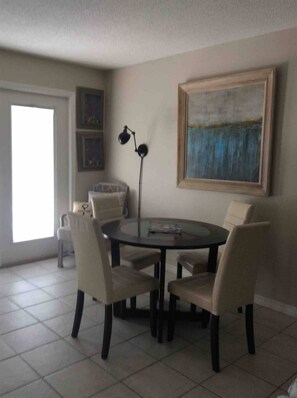 Un coin repas comprenant une table ronde et quatre chaises, un lampadaire et un tableau accroché au mur.