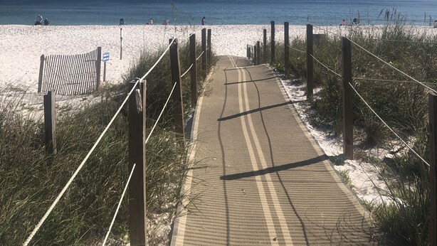 A pathway leading to a beach with a clear sky.
