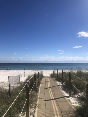 A pathway leading to a beach with a clear sky.