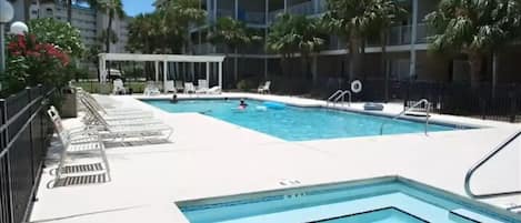 A swimming pool area with lounge chairs and a covered seating area.