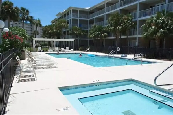 A swimming pool area with lounge chairs and a covered seating area.