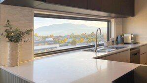 A modern kitchen with a large window, stainless steel sink, and a coffee maker. - Little Island Apartments (Bellerive)