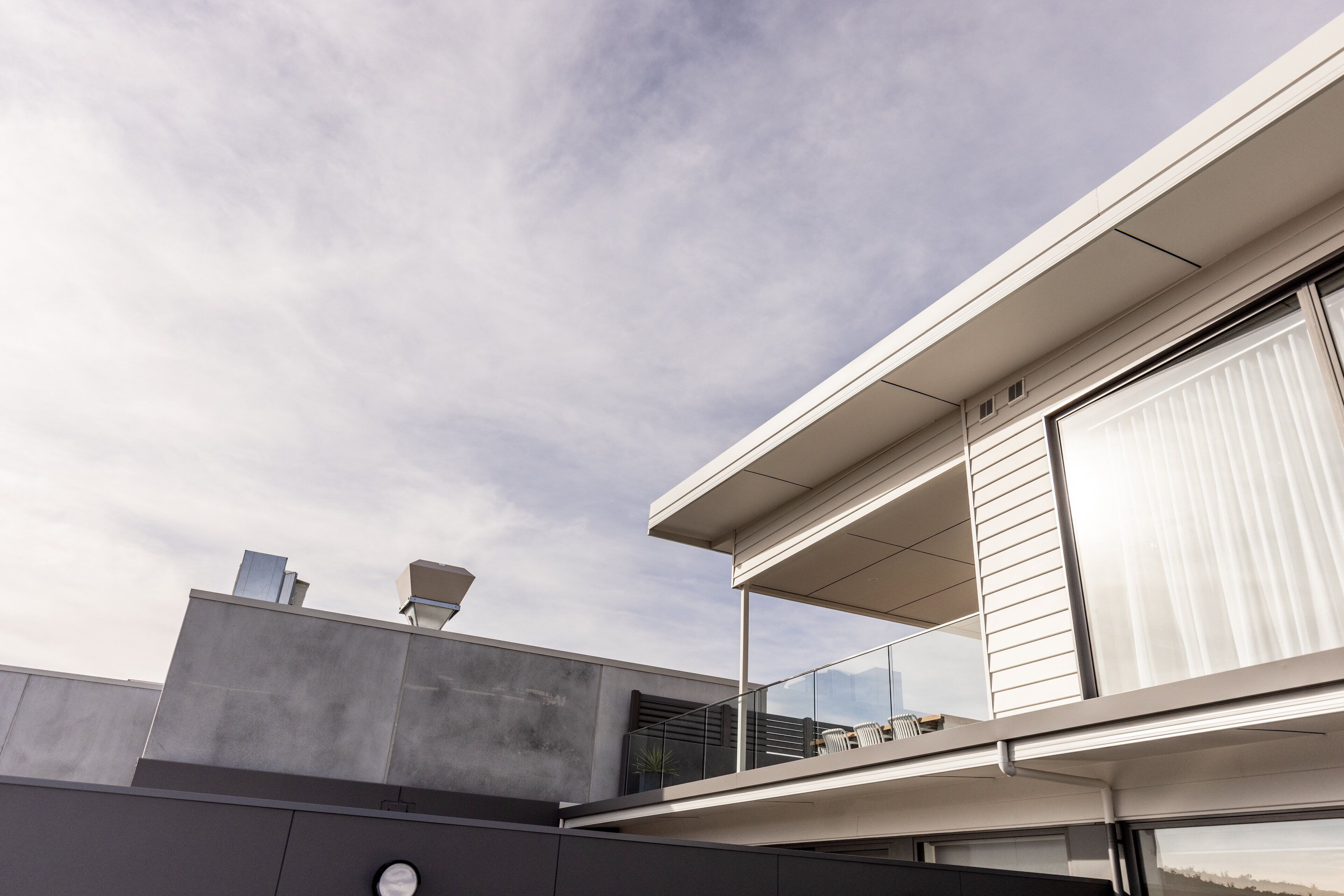 A modern building with a balcony, large windows, and a flat roof.