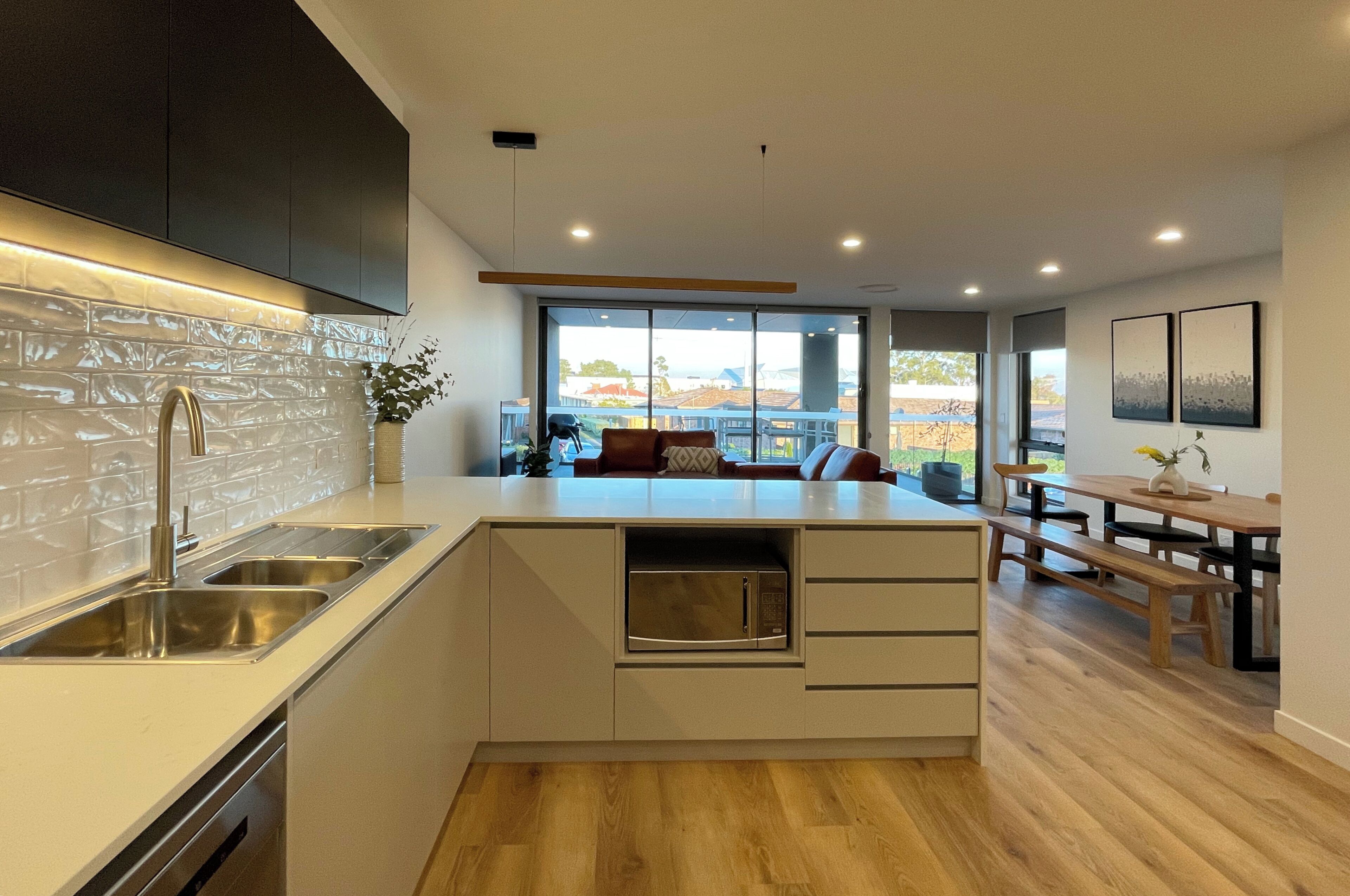 Una cocina moderna con microondas integrado, lavavajillas y un amplio ventanal con vistas al exterior.