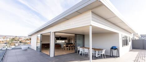 A modern house with a covered patio, a kitchen, and a dining area with outdoor seating.