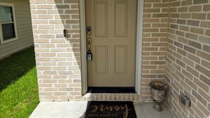 A beige front door with a mailbox, a doormat, and a potted plant beside it. - DREAM LAND (Porter)