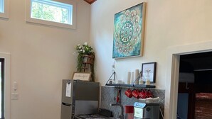 A compact kitchen with a wooden table, bar stools, a coffee maker, and a decorative wall piece. - Gunner's Goat House at Billy Goat Mountain Village (Williamson)
