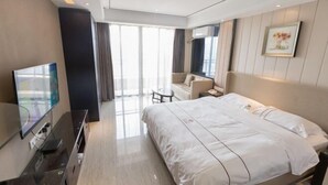 Een moderne hotelkamer met een groot bed, een flatscreen televisie, een klein tafeltje en een bank.
