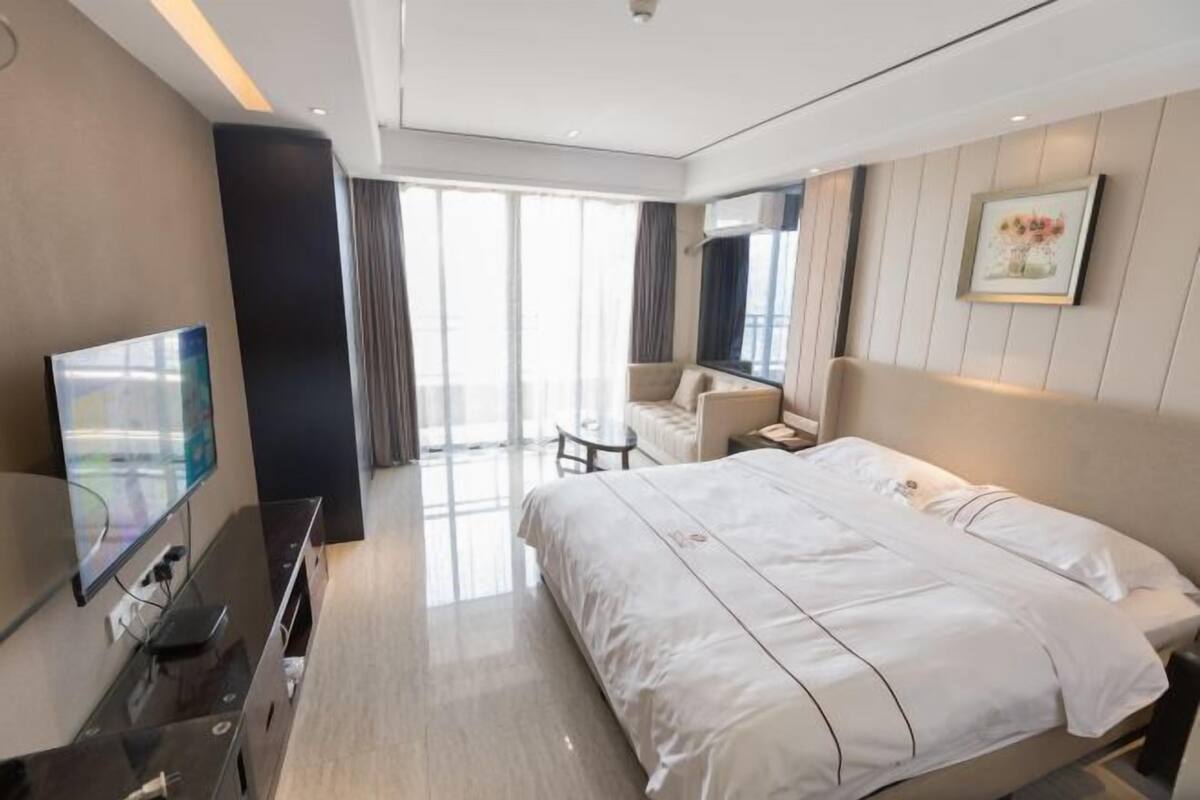 Een moderne hotelkamer met een groot bed, een flatscreen televisie, een klein tafeltje en een bank.