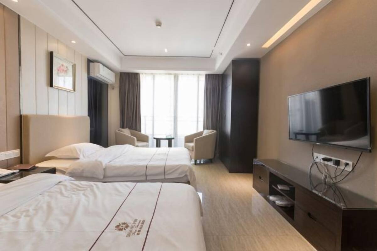 Een hotelkamer met twee bedden, een televisie, een tafeltje en een stoel.
