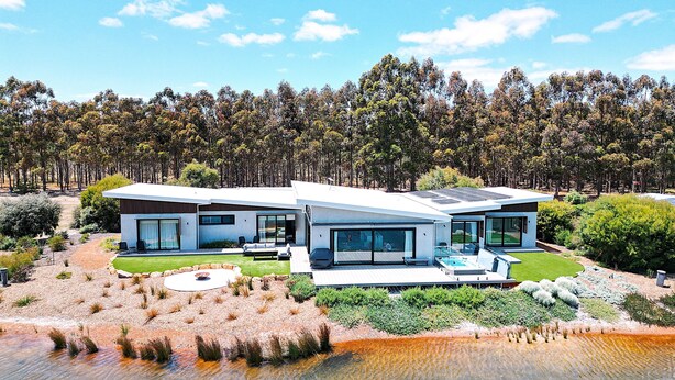 Una casa moderna de dos pisos con piscina, rodeada de un bosque.
