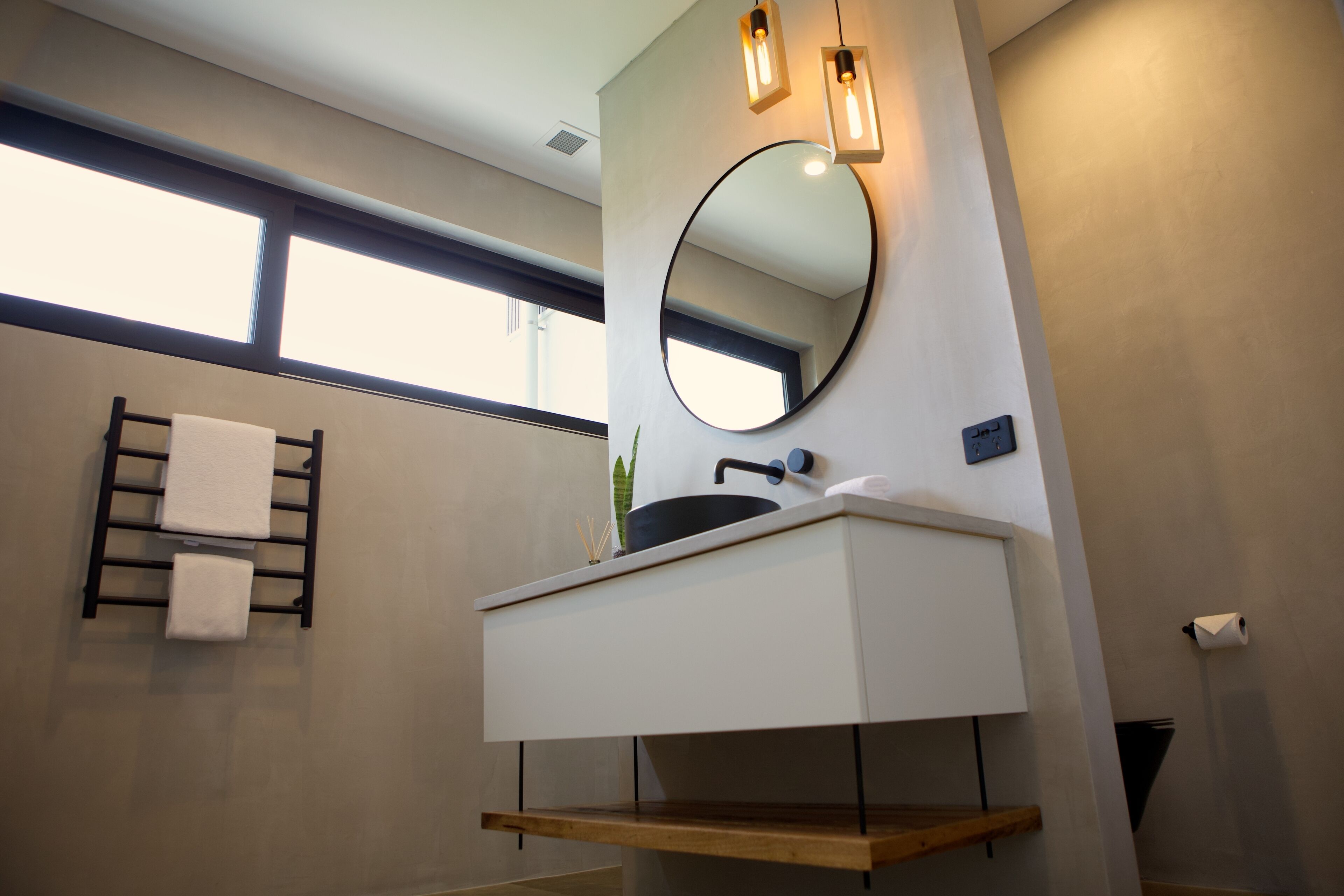 Un baño moderno con un espejo grande, un lavabo y un perchero para toallas.