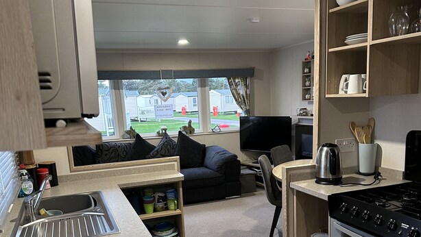 A compact kitchen with a built-in oven, a sink, and a dining area with a chair. - Come to the finest coast line in Britain! (Prestonpans)
