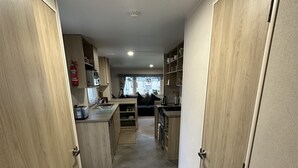 A compact kitchen with wooden cabinets, a microwave, and a toaster. A fire extinguisher is mounted on the wall. - Come to the finest coast line in Britain! (Prestonpans)