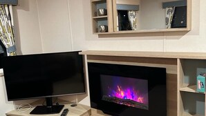 A living room with a flat-screen TV, a fireplace, and a wooden entertainment unit. - Come to the finest coast line in Britain! (Prestonpans)