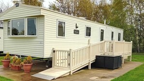 A mobile home with a ramp leading to the entrance, a covered porch, and potted plants. - Come to the finest coast line in Britain! (Prestonpans)