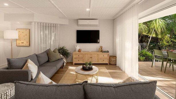 Uma sala de estar moderna com um sofá cinza, uma mesa de centro, uma televisão e um armário de madeira.