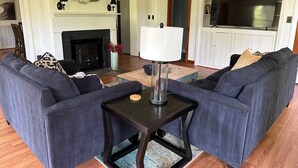 A living room with two grey sofas, a black coffee table, a fireplace, and a TV cabinet.