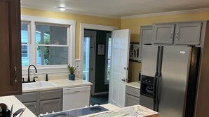 A modern kitchen with a central island, bar stools, a refrigerator, and a microwave.