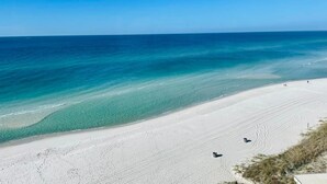 Een strand met helder turquoise water en wit zand.