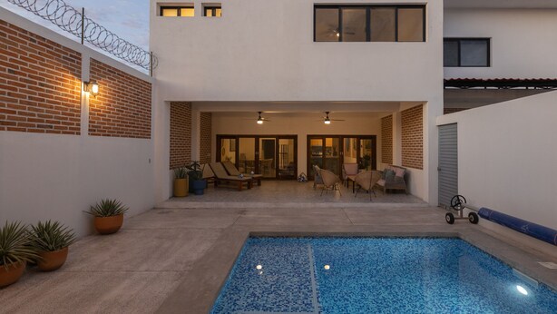 A modern outdoor pool area with a tiled floor, lounge chairs, and a small table. - Casa La Paz with pool, patio and bbq grill (La Paz)