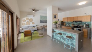 A modern kitchen with a bar area, wooden cabinets, and a dining area with a sofa and chairs. - Casa La Paz with pool, patio and bbq grill (La Paz)