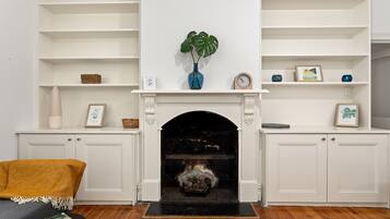 A living room with a fireplace, white shelving, and a woven chair.