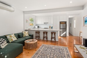 A modern living room with a green sofa, a coffee table, and a patterned rug. - Alkira House Victorian Retreat in Leafy Hawthorn (Hawthorn)