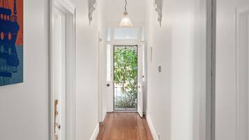 A hallway with white walls, a wooden floor, and a door with a metal gate.
