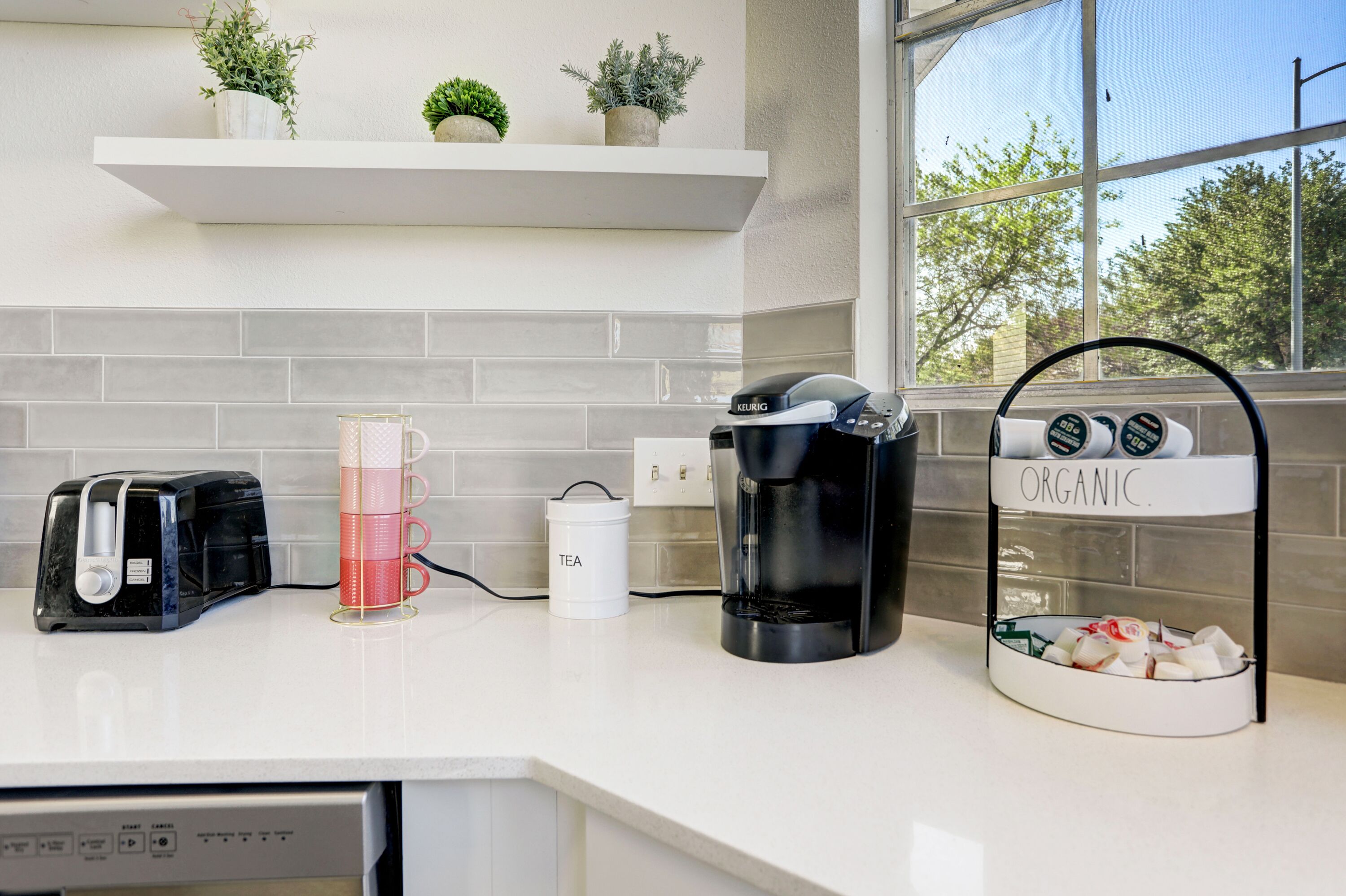 A kitchen with a coffee maker, a tea kettle, and a toaster on the counter.