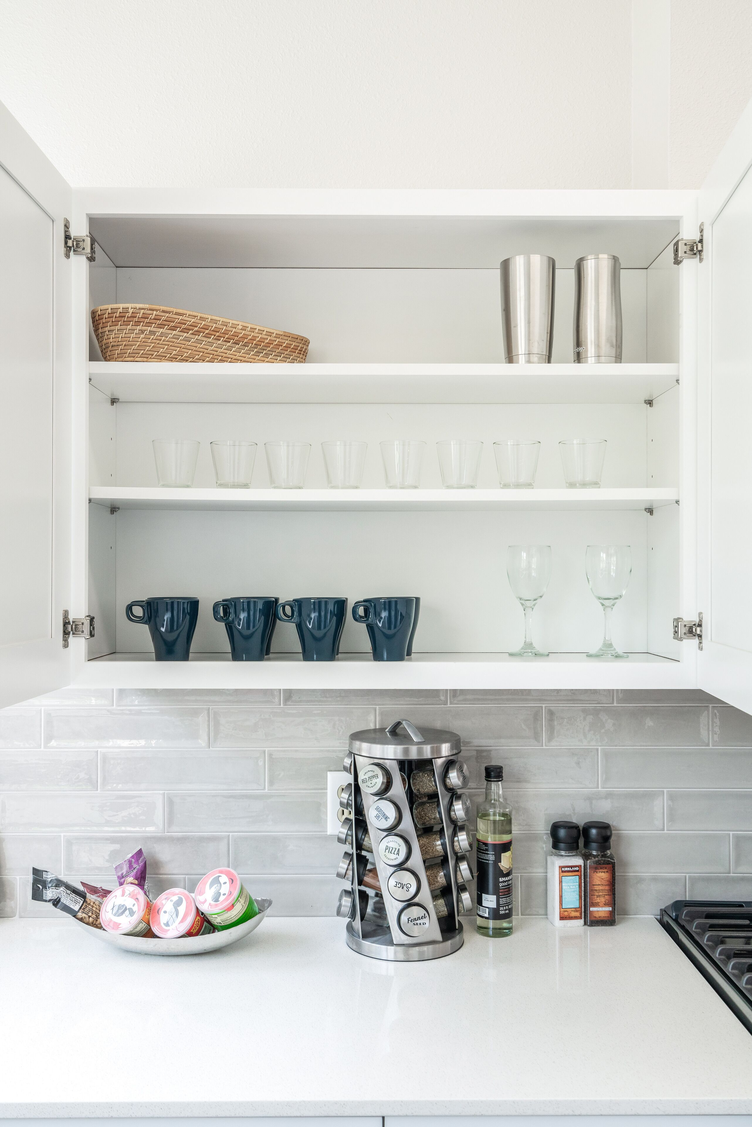 A kitchen with white cabinets, a coffee maker, and various kitchen items on the counter.