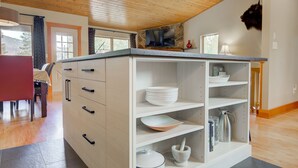 Eine Küche mit Holzbalkendecke, ein Essbereich mit einem roten Tisch und ein Kamin aus Stein.