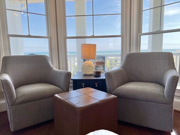 Una habitación con dos sillones estampados, una mesita con lámpara y vistas al océano.