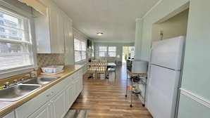 A kitchen with white cabinets, a wooden countertop, a sink, and a refrigerator. - The Reef Apartments Unit #2 - Downtown/5min walk to the beach! (Ocean City)