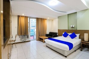A hotel room with a large bed, a desk, a chair, a TV, and a balcony with curtains. - Alley 8 Makati (Makati)