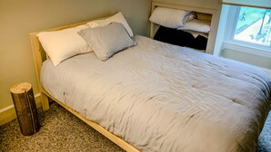 A bed with a wooden frame, two pillows, and a light-colored duvet. - Quirky Downtown Loft (Harrisburg)