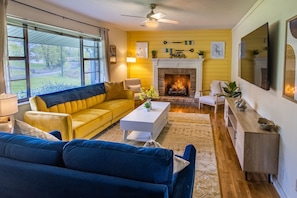 A living room with a yellow wall, a fireplace, a sofa, a coffee table, and a TV.