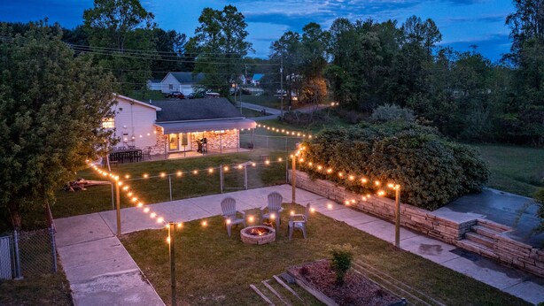 A backyard with a fire pit, outdoor seating, and string lights.