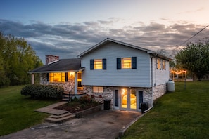 A two-story house with a brick chimney, a front porch, and a well-maintained lawn.