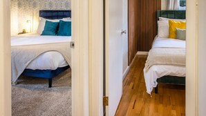 A hotel room with two beds, one with a blue headboard and the other with a green headboard.