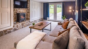 A cozy living room with a stone fireplace, a sofa, a coffee table, and a view through a glass door.