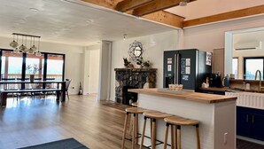A spacious kitchen with a stone fireplace, wooden bar stools, and a large island.