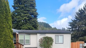 A single-story house with a front porch, a small front yard, and a mountain backdrop.